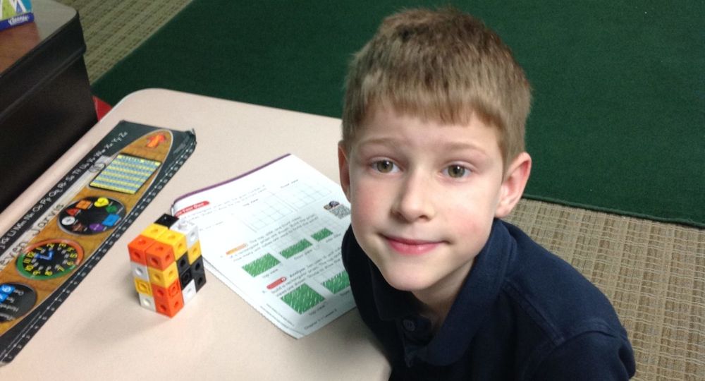 Smiling Pike elementary student with math cubes and a workbook